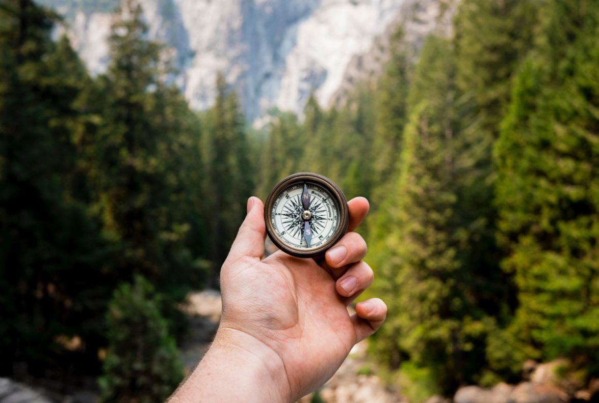 Hand holding compass up to set a course through the wilderness